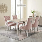 A 5-piece dining set featuring a rectangular marble-top table with a chrome frame and four blush pink tufted and quilted velvet chairs with silver legs, shown in a bright, modern dining room.