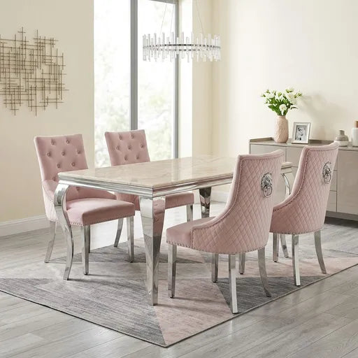 A 5-piece dining set featuring a rectangular marble-top table with a chrome frame and four blush pink tufted and quilted velvet chairs with silver legs, shown in a bright, modern dining room.