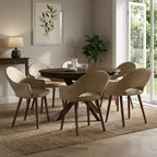A 7-piece dining set featuring a round dark wood table and six upholstered chairs in beige velvet, styled in a bright, modern dining room.