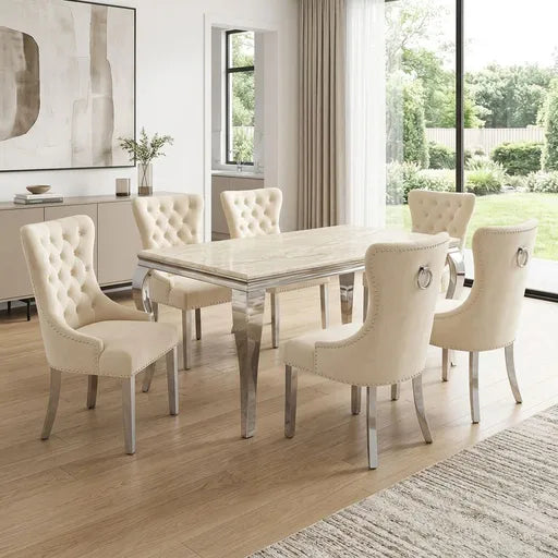 A 7-piece dining set featuring a rectangular table with a light marble top and mirrored silver legs, surrounded by six tufted cream upholstered dining chairs with silver metal legs.
