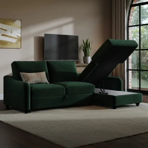 A dark green upholstered sectional sofa with a chaise lounge and raised lift-up ottoman, shown in a styled living room setting with a beige rug, wall art, and a window.