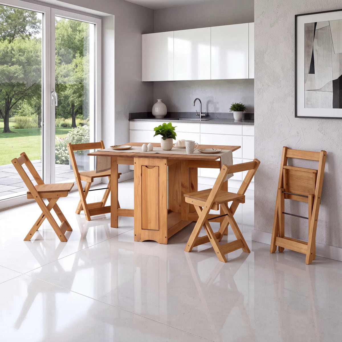 A light natural wood dining set consisting of a rectangular folding table and four matching folding chairs, displayed in a modern, bright kitchen with white cabinets and large windows.