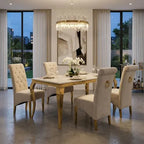 A luxury dining room set featuring a rectangular marble-top dining table with gold legs, surrounded by six tufted cream upholstered chairs with gold ring accents. The set is styled in a modern dining room with a crystal chandelier, large windows, and a concrete floor.