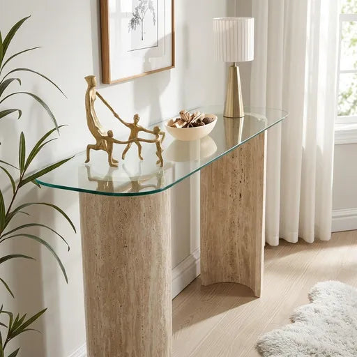 A modern console table with a curved clear glass top and two textured beige stone legs, .