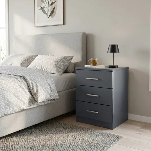 A modern three-drawer nightstand in dark gray with silver handles, positioned next to a light gray 