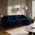 A navy blue velvet sectional sofa with a chaise lounge, styled in a modern, elegant living room with wood paneling, a cream rug, and a marble coffee table.