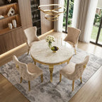 A round marble-top dining table with gold legs, surrounded by four tufted blush-beige upholstered chairs, shown in a modern dining room setting on a gray rug.