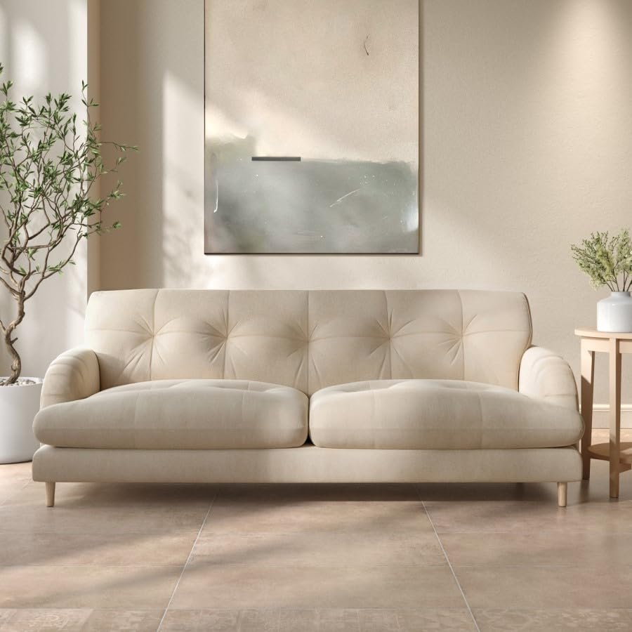 Beige sofa in a living room setting with a mirror and plants.