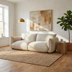 Beige sofa in a living room with abstract art, lamp, and plant.