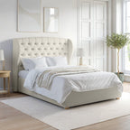 Beige upholstered bed in a bright bedroom with light wood flooring and white walls.