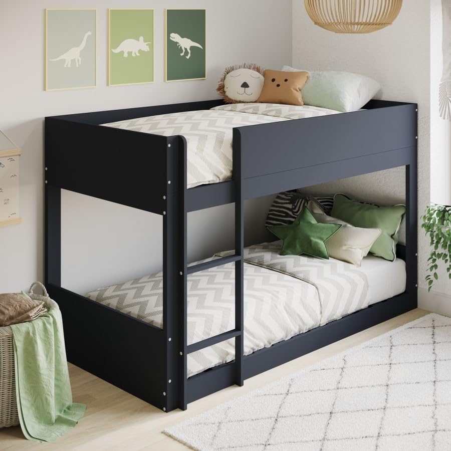 Black bunk bed with white bedding in a child's bedroom with dinosaur posters on the wall.