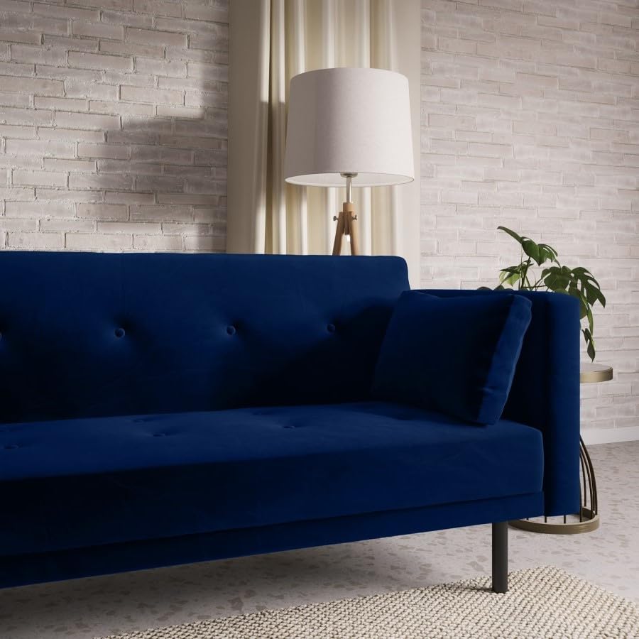 Blue sofa in a room with a lamp and plant against a brick wall.