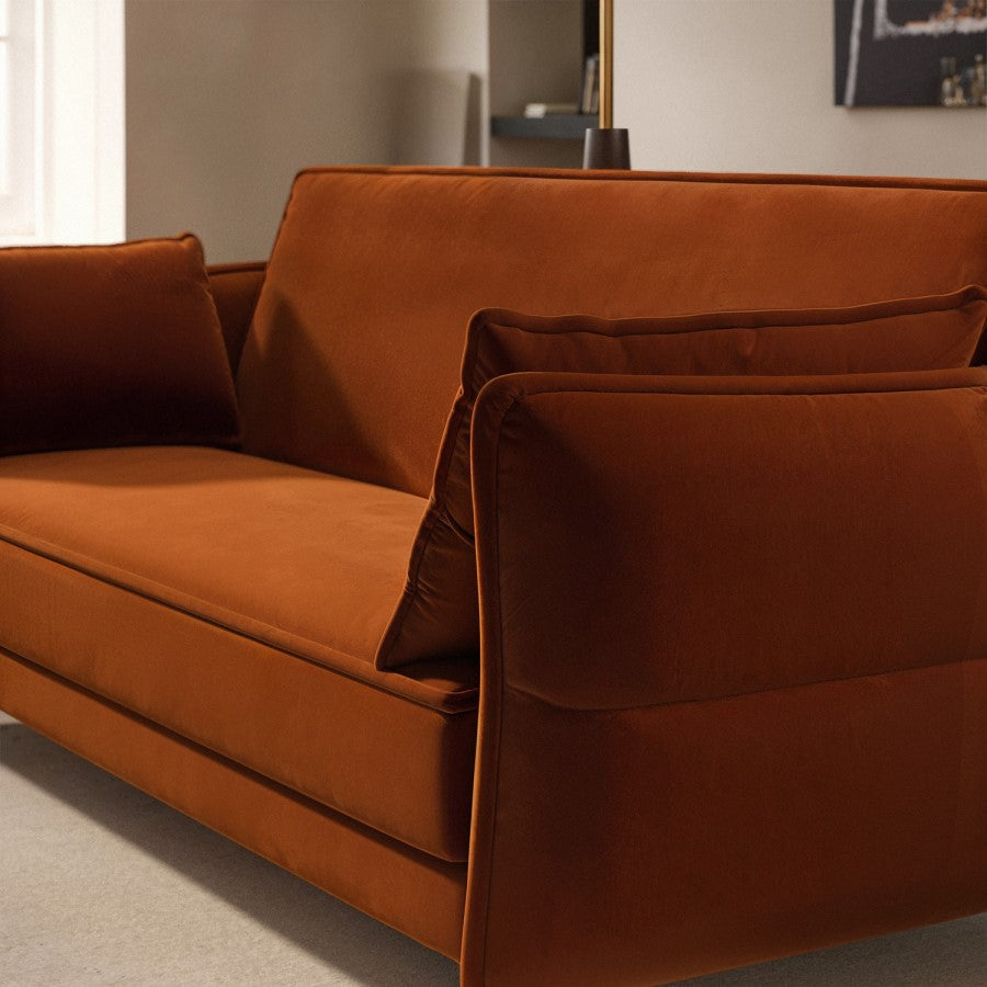 Burnt orange sofa bed with cushions in a room setting