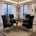 A luxury dining room set featuring a rectangular black marble-top table with gold legs, surrounded by four high-back cream tufted velvet chairs with gold legs and ring pulls, set in a modern high-rise apartment.
