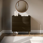 Dark brown dresser with three drawers in a room with a round mirror on the wall.