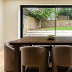 Dining area with a wooden table and chairs in front of a sliding glass door.