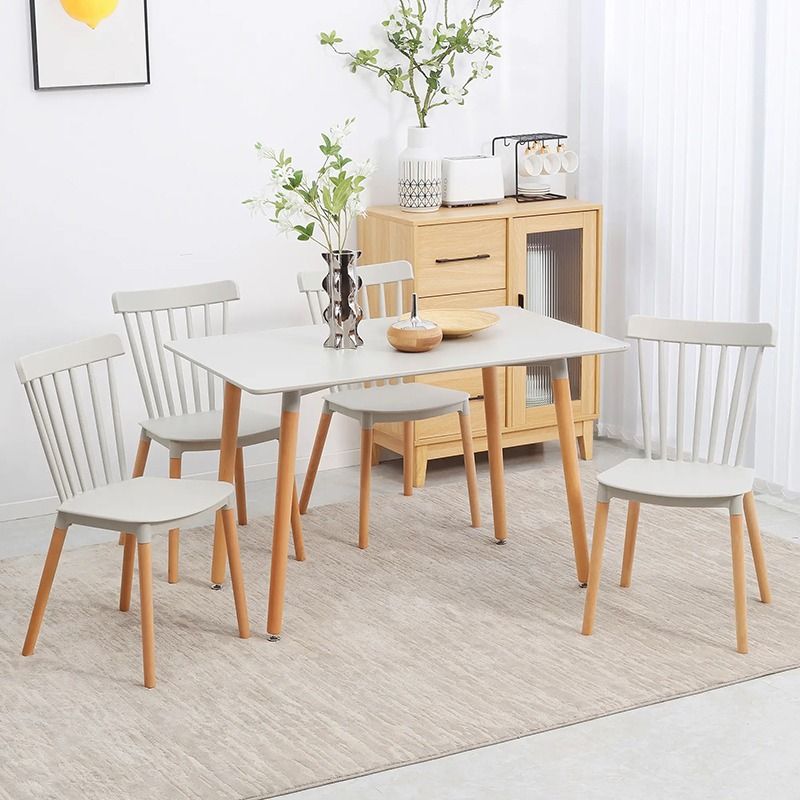 Dining room set with a white table and wooden chairs in a bright room.