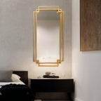 Gold-framed mirror on a wall above a nightstand in a bedroom setting.