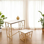 Gold-framed table and chair set with marble top in a room with plants and curtains.
