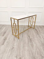 Gold console table against a white wall on a wooden floor