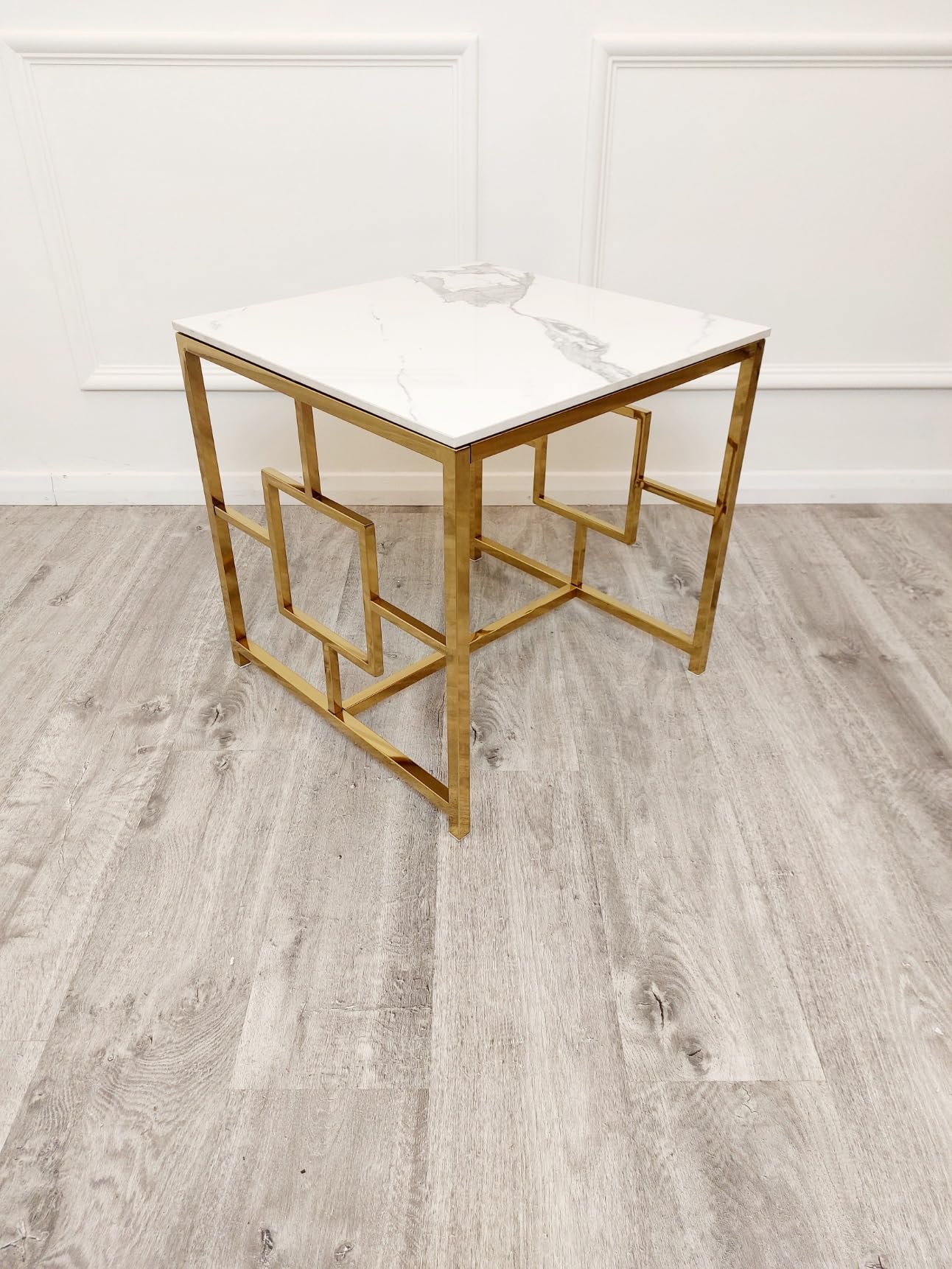Gold-framed glass table with white surface on a wooden floor