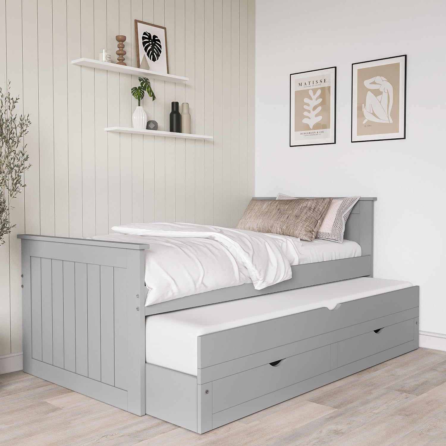 Gray bed with white bedding in a room with shelves and wall art.