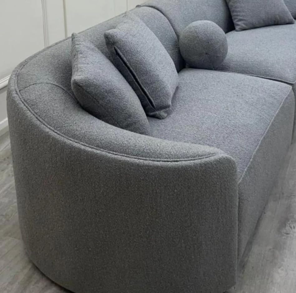 Gray curved sofa with cushions in a minimalistic room.