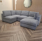 Gray sectional sofa in a room with wooden flooring and a mirror on the wall.