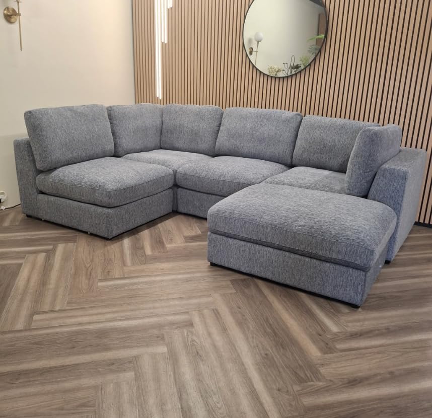 Gray sectional sofa in a room with wooden flooring and a mirror on the wall.