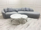 Gray sectional sofa with two round coffee tables on a light wood floor.