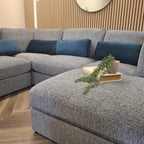 Gray sectional sofa with blue cushions and decorative items in a living room setting.