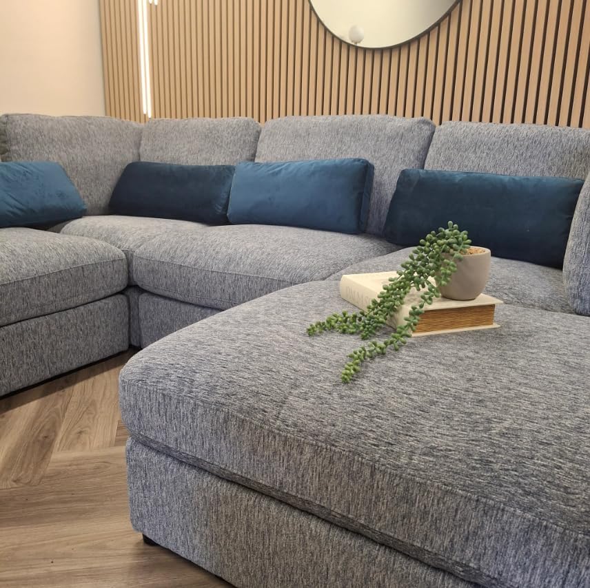 Gray sectional sofa with blue cushions and decorative items in a living room setting.
