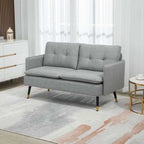Gray sofa in a living room setting with a rug and side table.