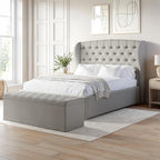 Gray upholstered bed with tufted headboard in a bright bedroom setting