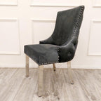 Gray upholstered chair with nailhead trim on a wooden floor.