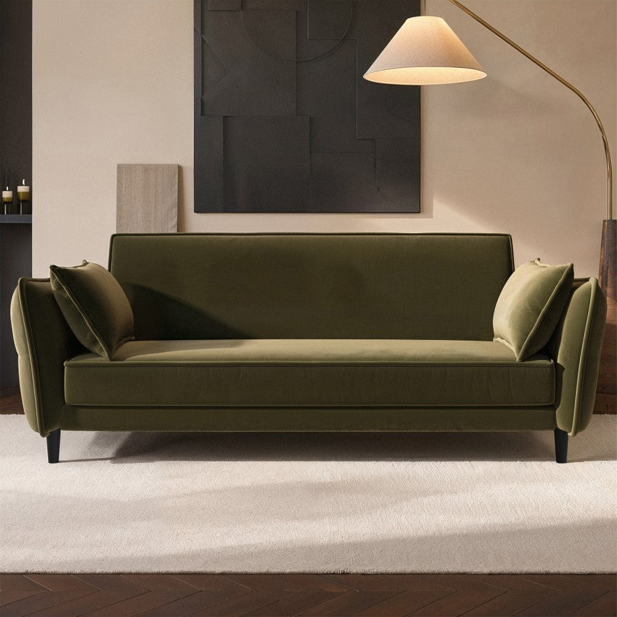 Green sofa bed in a modern living room setting with a lamp and artwork on the wall.