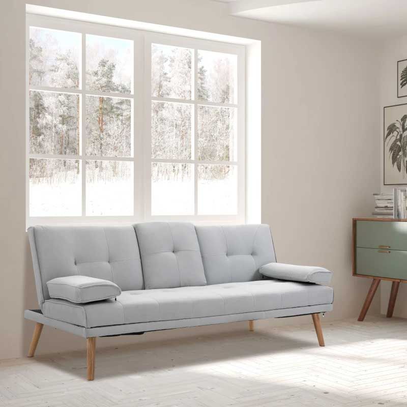 Light gray sofabed with wooden legs in a bright room with large window