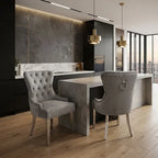 A modern kitchen and dining area featuring two tufted gray velvet dining chairs with silver nailhead trim and light wood legs