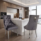 Two gray tufted velvet dining chairs with silver nailhead trim and chrome legs