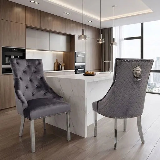 Two gray tufted velvet dining chairs with silver nailhead trim and chrome legs