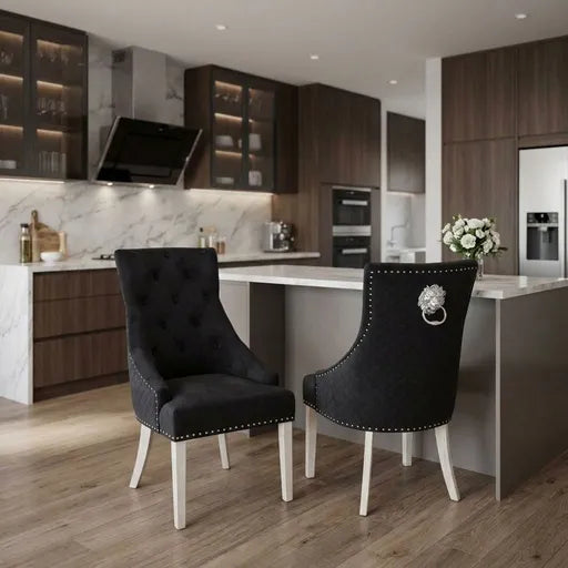 Two modern black tufted dining chairs with white legs and silver nailhead trim