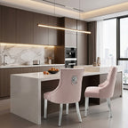 Two blush pink upholstered dining chairs with silver legs, shown in a real interior environment.