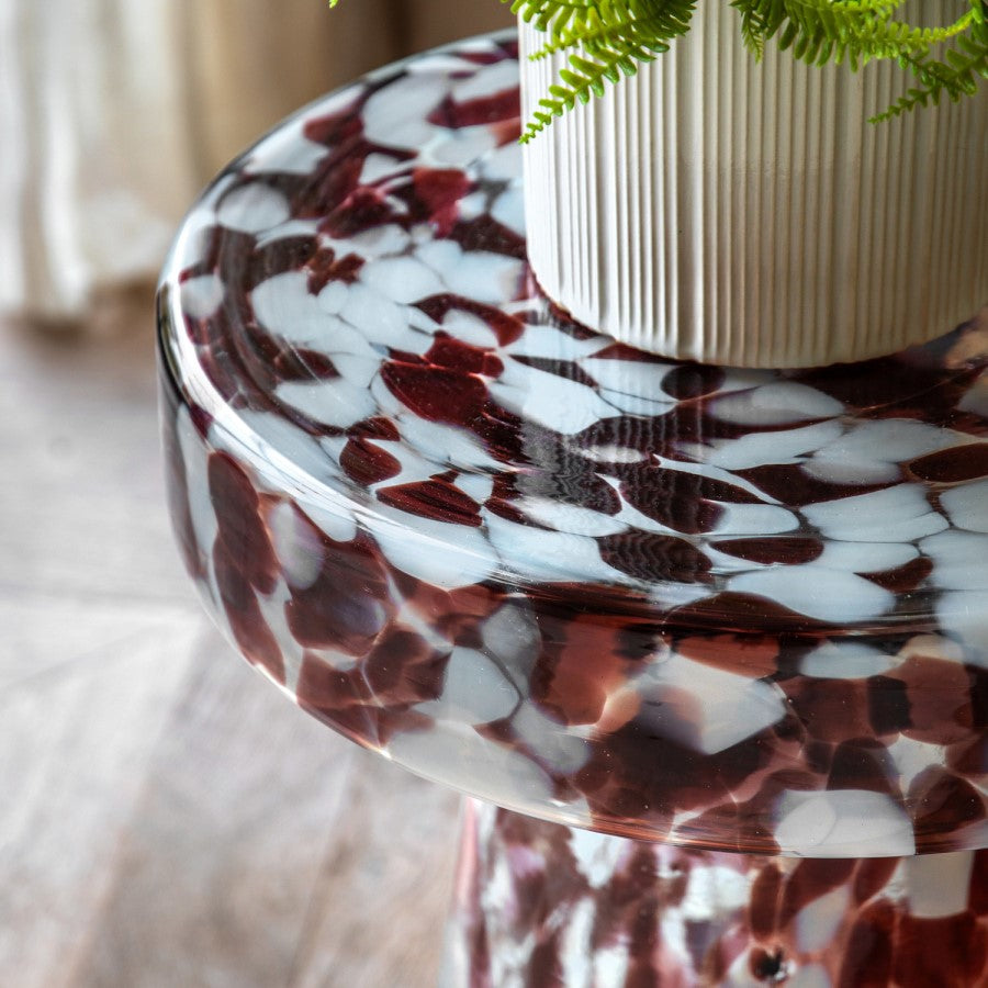 Marbled red and white table with a plant on a blurred background