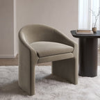 Modern beige armchair in a room with a table and decor items.