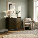Modern interior with a dark brown dresser, beige armchair, and abstract art on a light green wall.