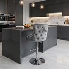 Modern kitchen with a gray island and bar stool, featuring black cabinets and marble countertops.