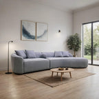 Modern living room with a gray sectional sofa, round wooden coffee table, and abstract art on the wall.