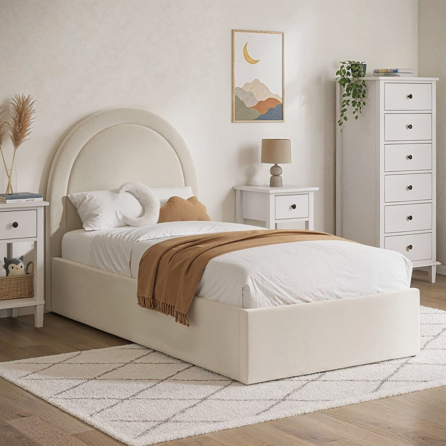 Neatly made bed with beige headboard in a bedroom setting.