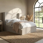 Neatly made bed with white bedding and a beige blanket in a bright bedroom.