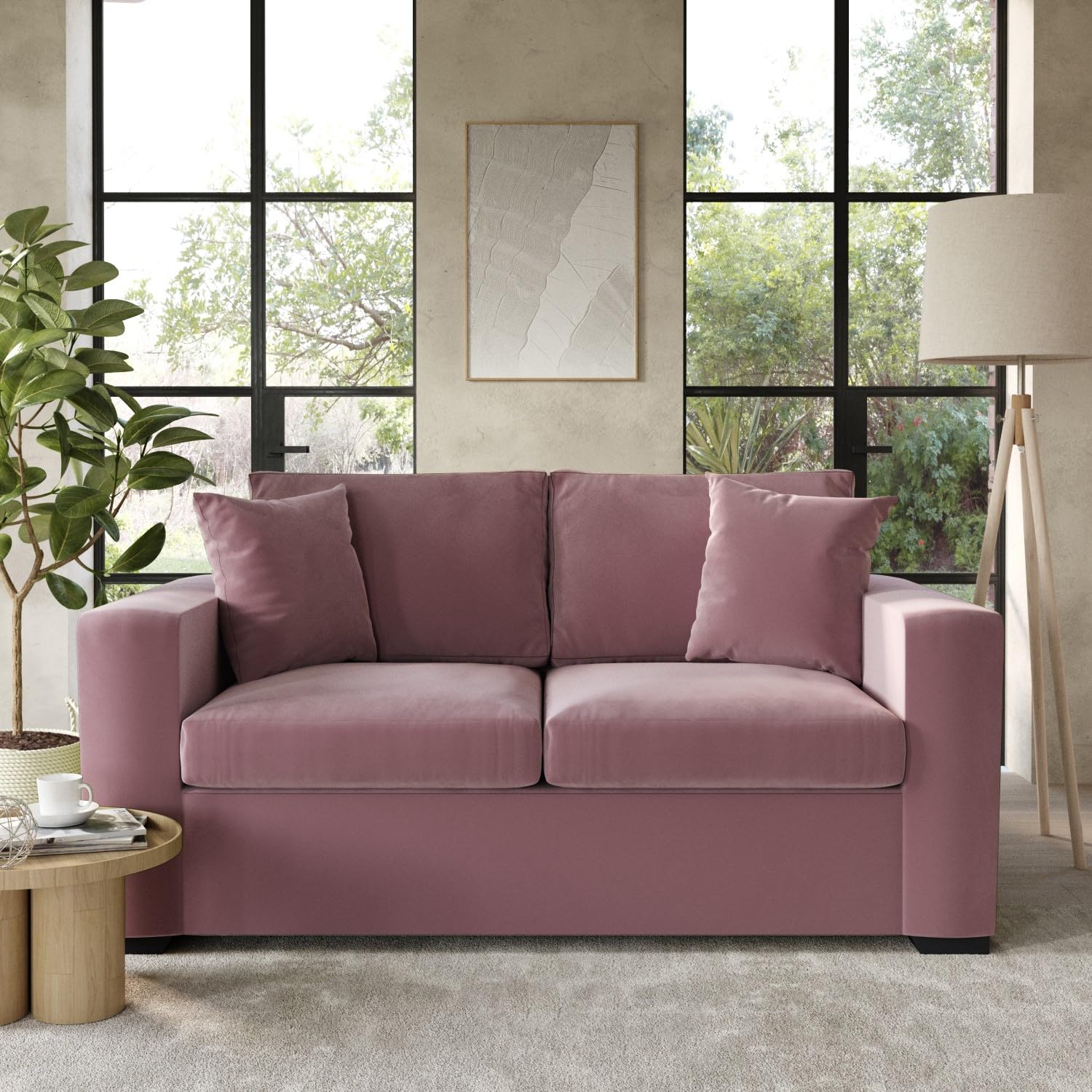 Pink sofabed in a living room with large windows and a lamp.